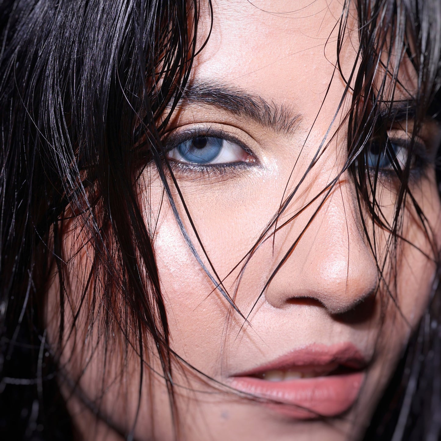 Close-up of a person with wet hair and blue eyes.